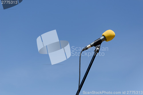 Image of yellow microphone on blue sky background 