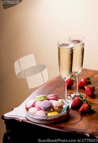 Image of Two glasses of sparkling wine or champagne with small colorful macaroons