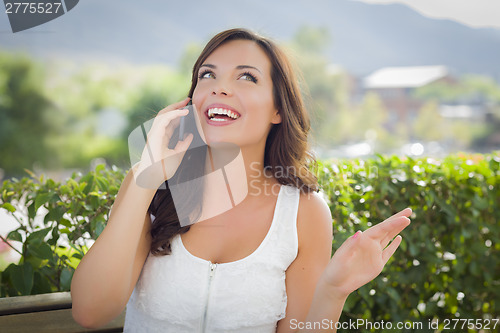 Image of Young Adult Female Talking on Cell Phone Outdoors on Bench