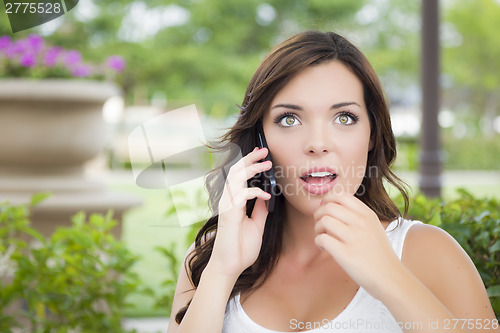 Image of Stunned Young Adult Female Talking on Cell Phone Outdoors