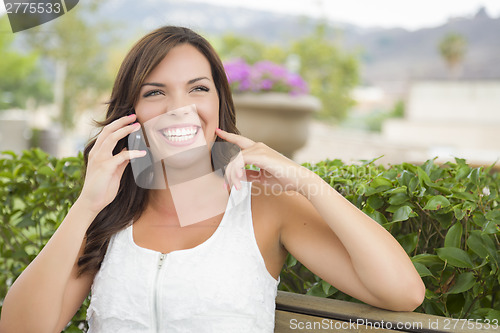 Image of Young Adult Female Talking on Cell Phone Outdoors on Bench