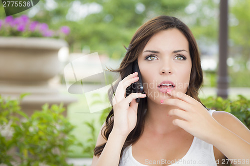 Image of Stunned Young Adult Female Talking on Cell Phone Outdoors