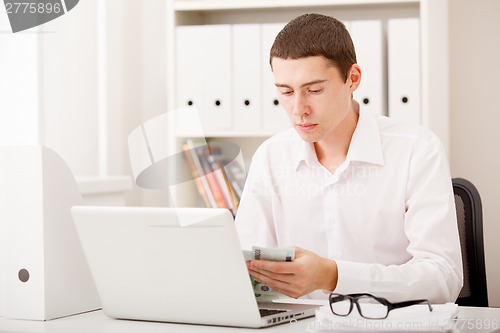 Image of man with laptop and money