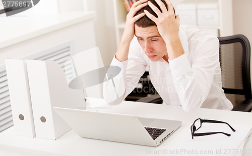 Image of Despairing businessman sitting at desk