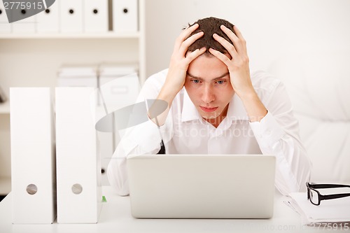 Image of Despairing businessman sitting at desk