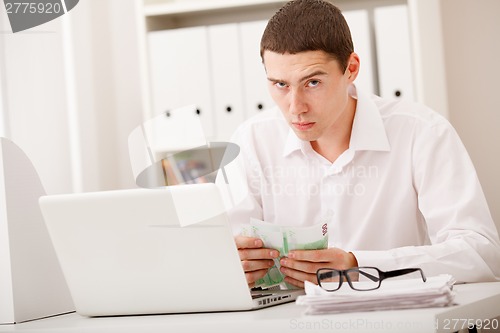 Image of man with laptop and money