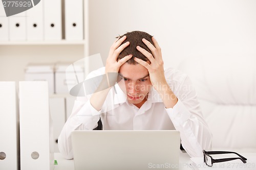 Image of Despairing businessman sitting at desk