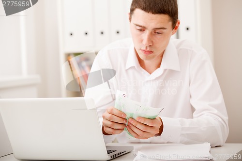 Image of man with laptop and money