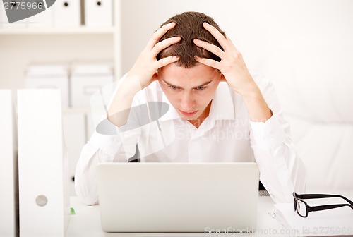 Image of Despairing businessman sitting at desk