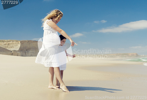 Image of Pregnant woman and her daughter on the beach