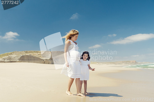 Image of Pregnant woman and her daughter on the beach