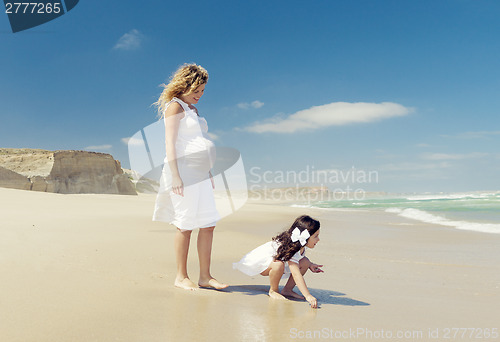 Image of Pregnant woman and her daughter on the beach