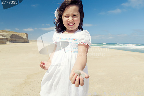 Image of Girl on the beach holding stones