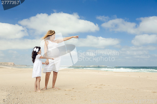 Image of Pregnant woman and her daughter on the beach