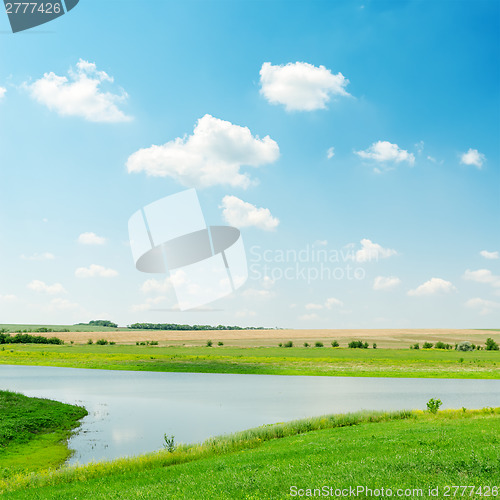 Image of river in green grass under cloudy sky