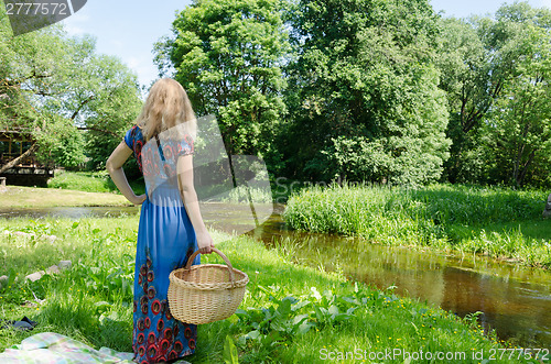 Image of woman standing with wicker basket in meadow