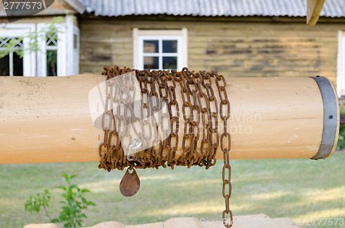 Image of close up wooden well roller with chain in country  