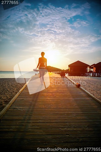 Image of Silhouette of a girl walking along the pier at sunset