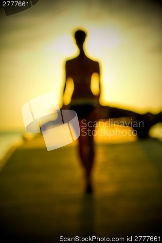 Image of Silhouette of a girl walking along the pier at sunset
