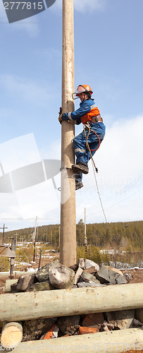 Image of Electrician begins to climb on a power pole 