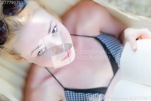 Image of Lady reading book in hammock.