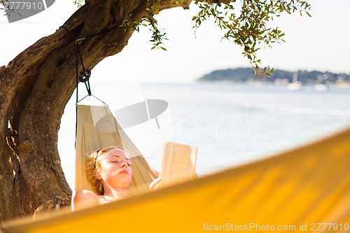 Image of Lady reading book in hammock.