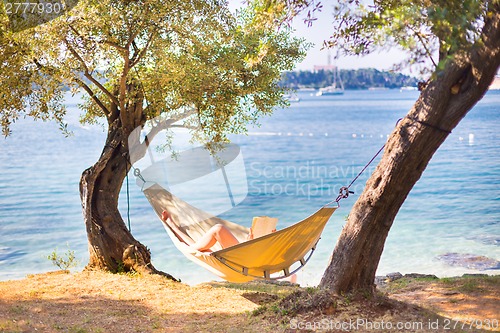 Image of Lady reading book in hammock.