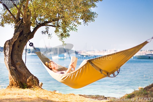 Image of Lady reading book in hammock.