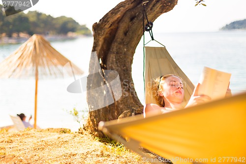 Image of Lady reading book in hammock.