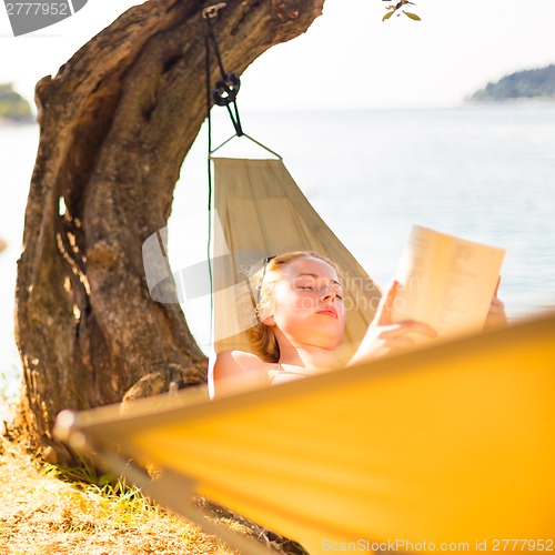 Image of Lady reading book in hammock.