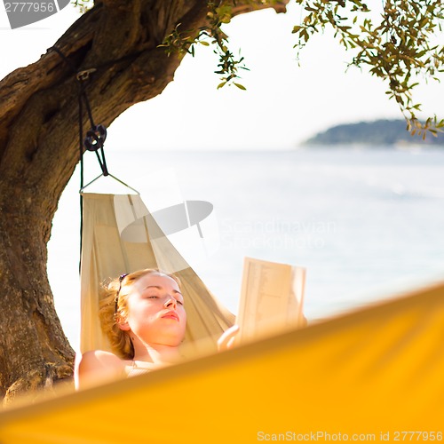 Image of Lady reading book in hammock.