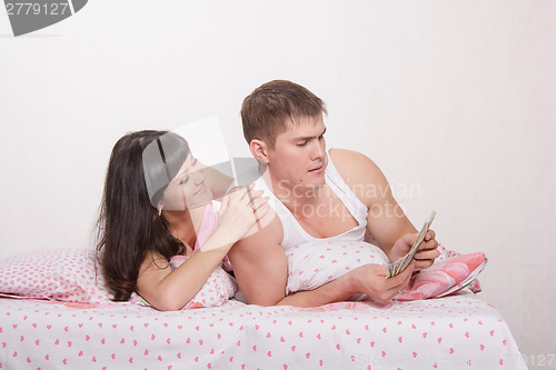 Image of Husband thinks money. Wife fawns