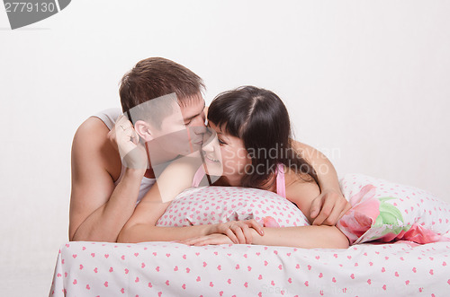Image of Girl with a guy in bed kissing