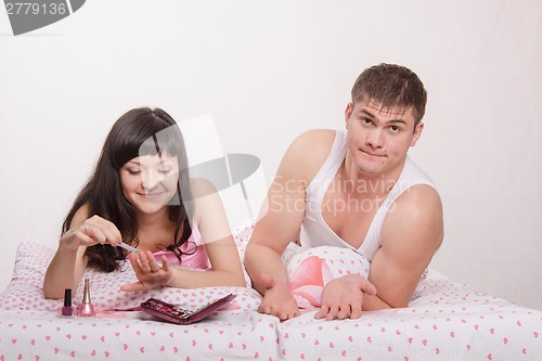 Image of Woman tired of waiting for guy that deals with manicure