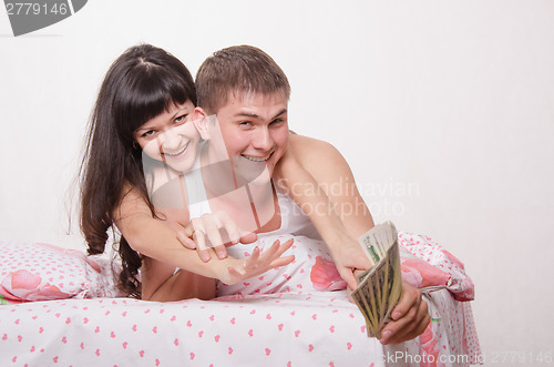 Image of Husband and wife are fighting for pack dollars in bed