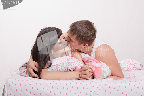 Image of Young boy kissing a girl in bed