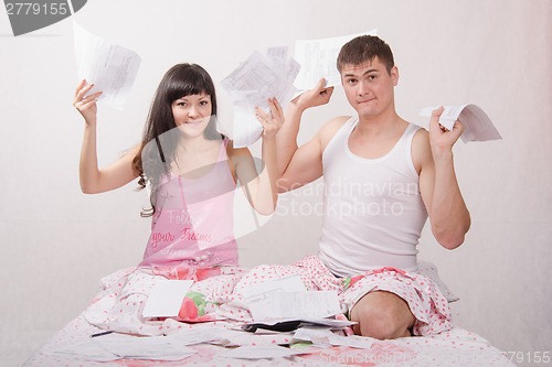 Image of Young family with bills for apartment sits in bed