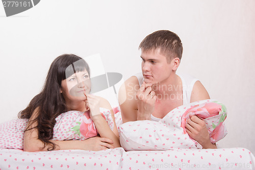 Image of young girl and guy thinking while lying in bed