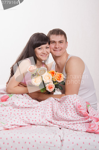 Image of Happy young beautiful couple sitting in bed