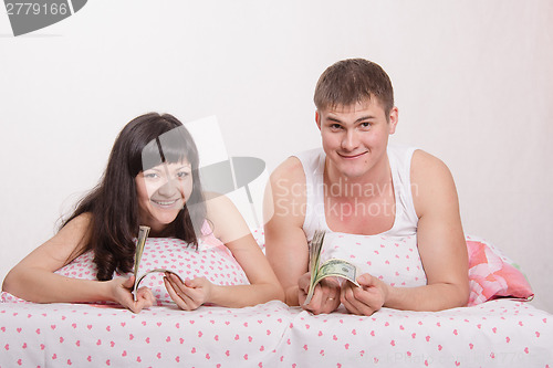 Image of girl and guy with a wad of dollars in bed