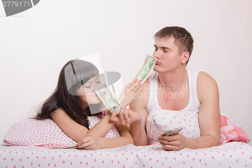 Image of Girl and guy sniffing smell of money in bed