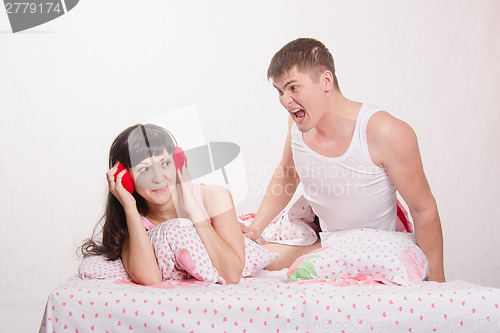 Image of Man strongly shouts at girl in headphones