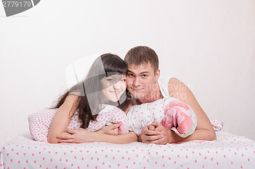 Image of Girl and guy lie embracing in bed