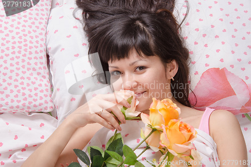Image of Beautiful girl lying in bed and enjoy scent of flowers