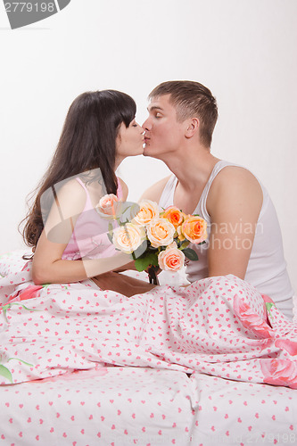 Image of girl and a guy sitting in bed kissing