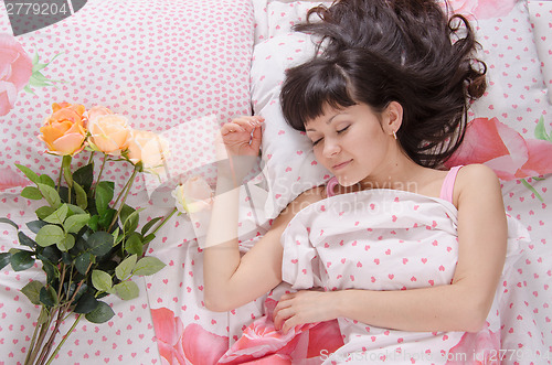 Image of On bed next to sleeping young girl lay flowers