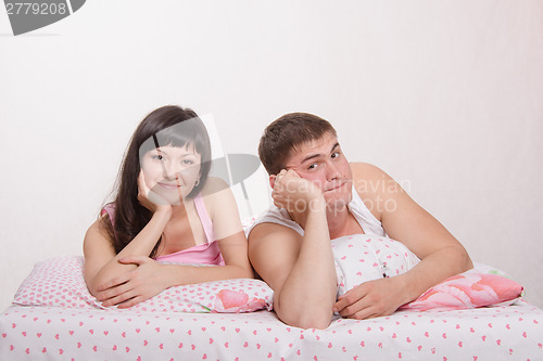 Image of Young happy woman and man relaxing in bed