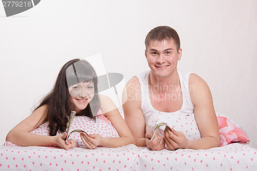 Image of girl and guy with a wad of money in bed