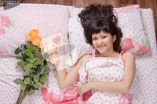 Image of Young happy girl on the bed of flowers