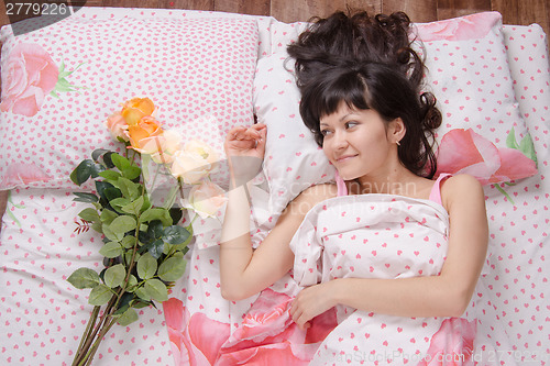 Image of girl wakes up and enjoys bouquet of flowers donated by